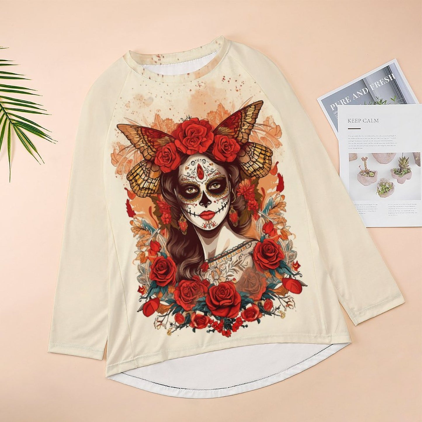 Long-sleeve shirt with a colorful design of a woman with a skull makeup and flowers on a beige background.