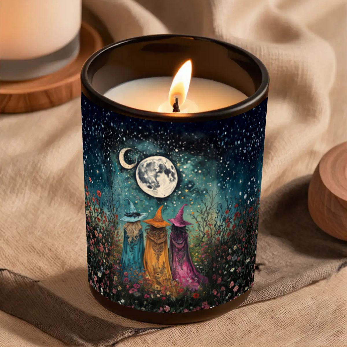 Candle in a decorative container with witch design and flame on a textured surface
