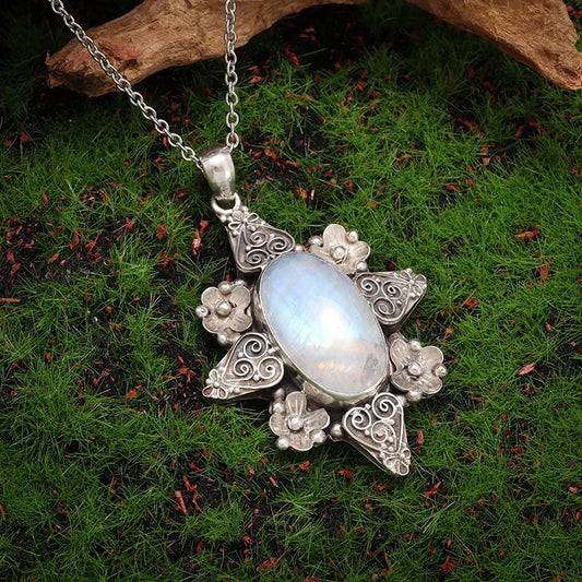 Silver pendant with a central gemstone on a green moss background