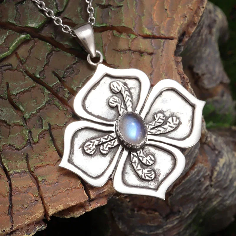 Silver floral pendant with a central gemstone on a wooden background