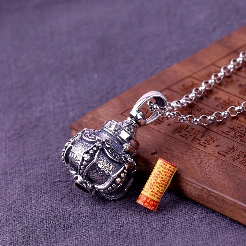 Silver pendant on a chain with a small red box on a wooden surface