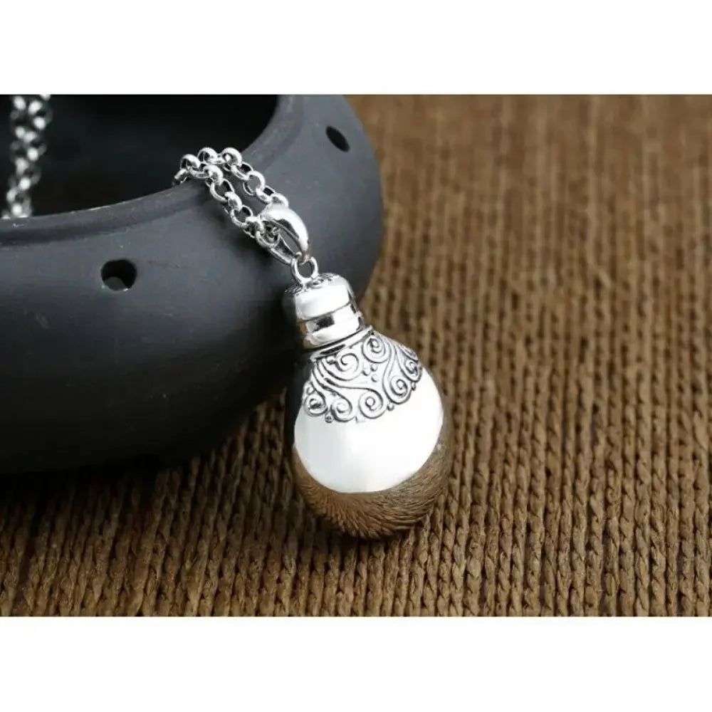 Silver pendant on a chain against a textured brown background