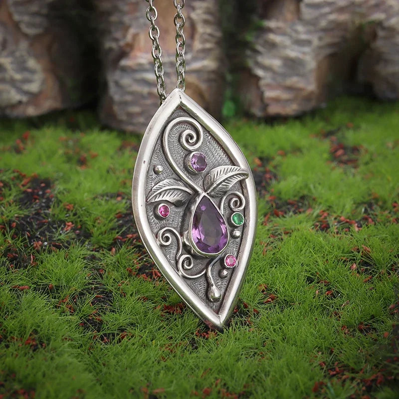Silver pendant with purple gemstone on grass