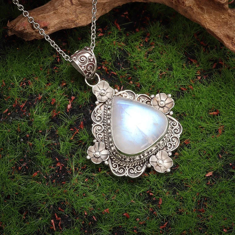 Silver pendant with a heart-shaped gemstone on a grassy background
