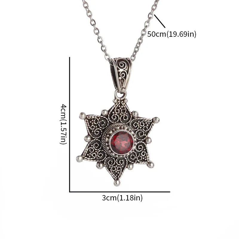 Star-shaped silver pendant with a red gemstone on a white background