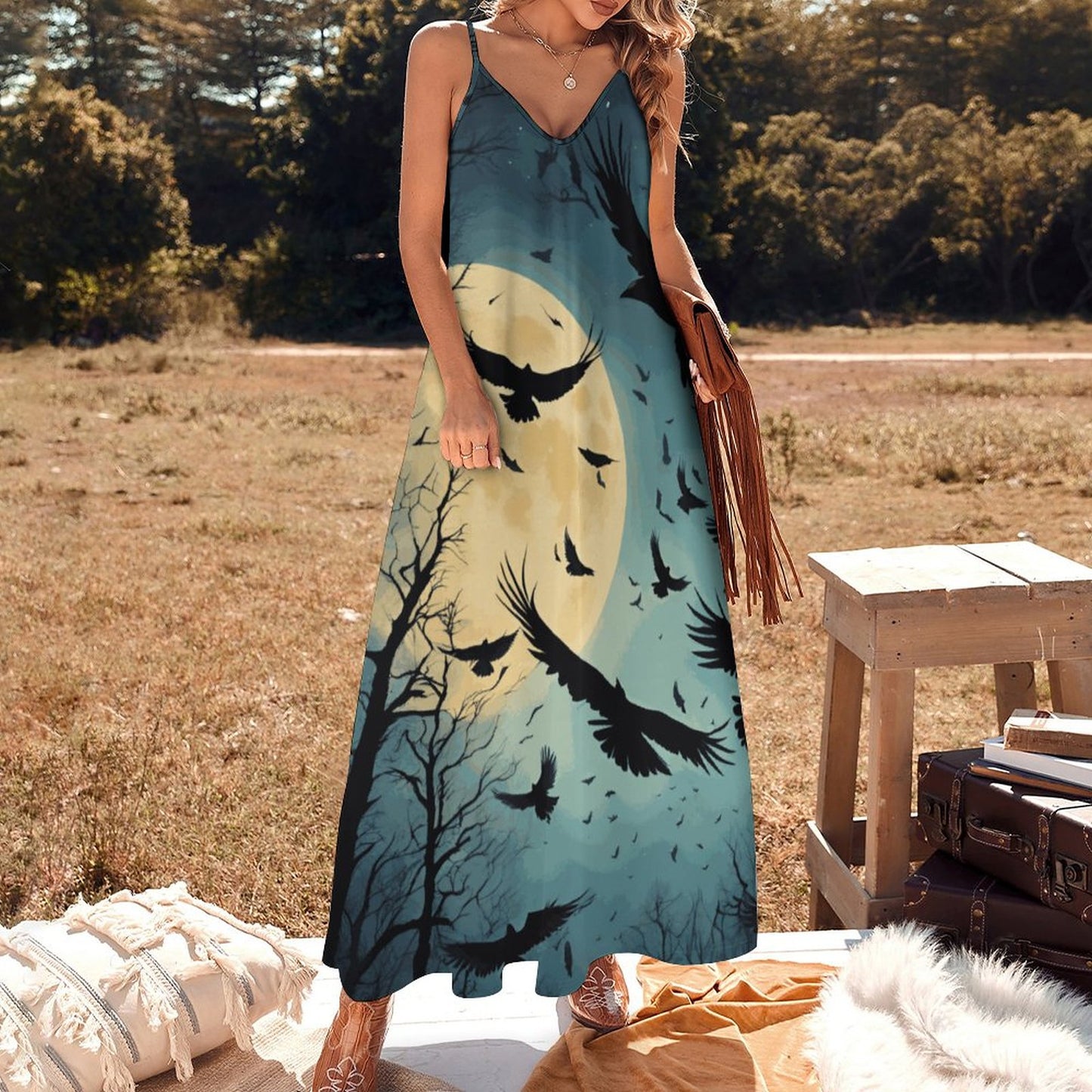 Woman wearing a dress with a moon and bird design in an outdoor setting.