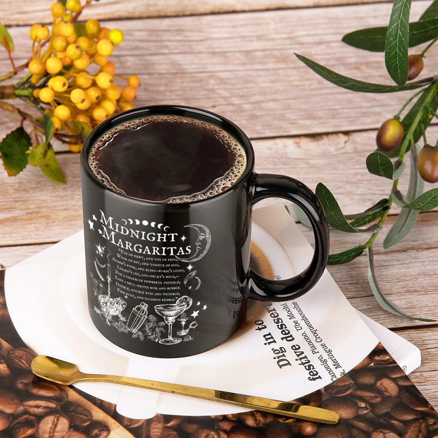 Black mug with 'Midnight Margaritas' design on a wooden surface with coffee beans and a plant.