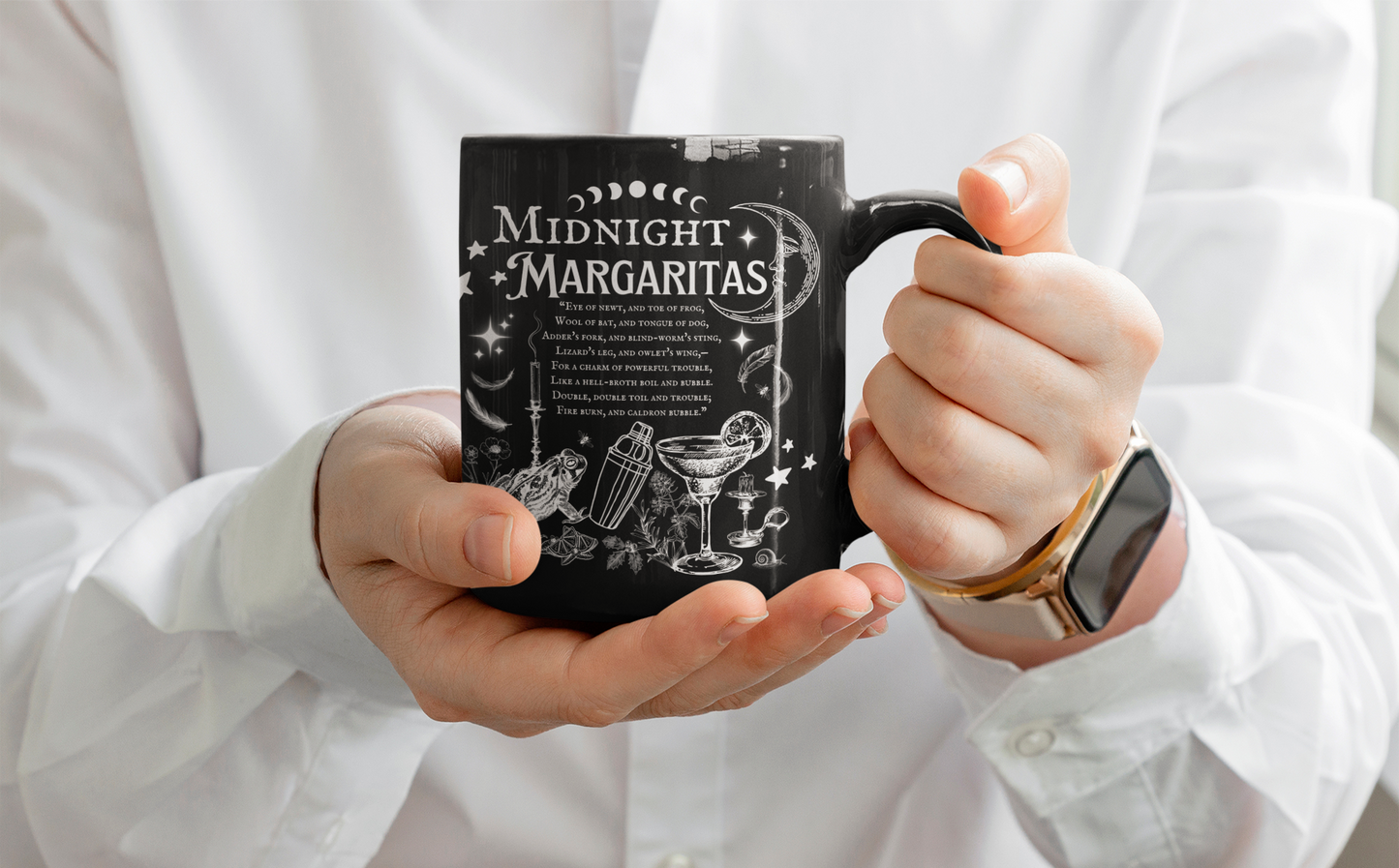 Person holding a black mug with 'Midnight Margaritas' text and graphics.