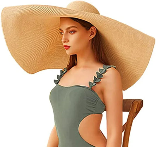 Woman wearing a large straw hat and green swimsuit with leaf straps on a white background