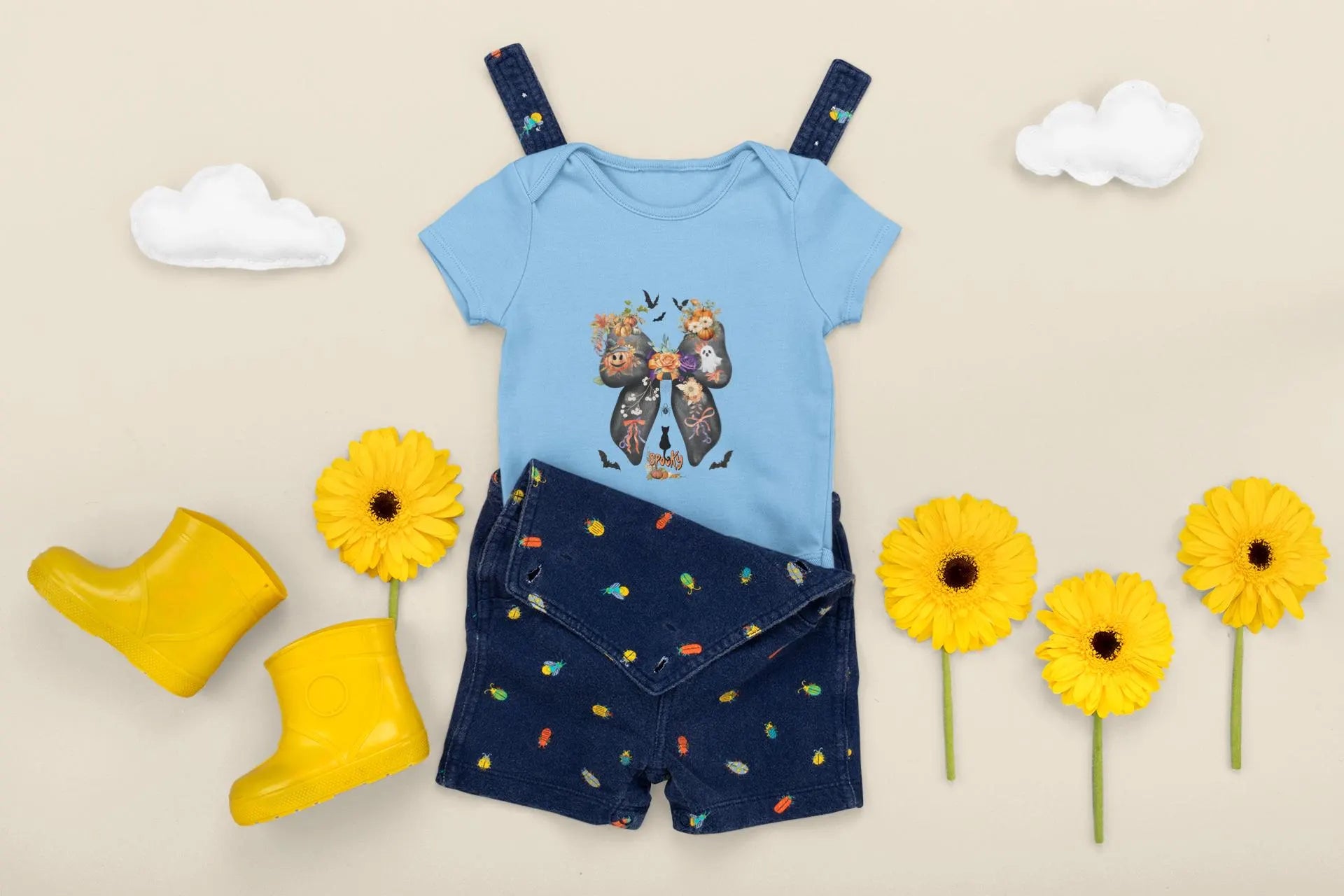 Baby outfit with blue romper and navy shorts, yellow boots, and flowers on a beige background