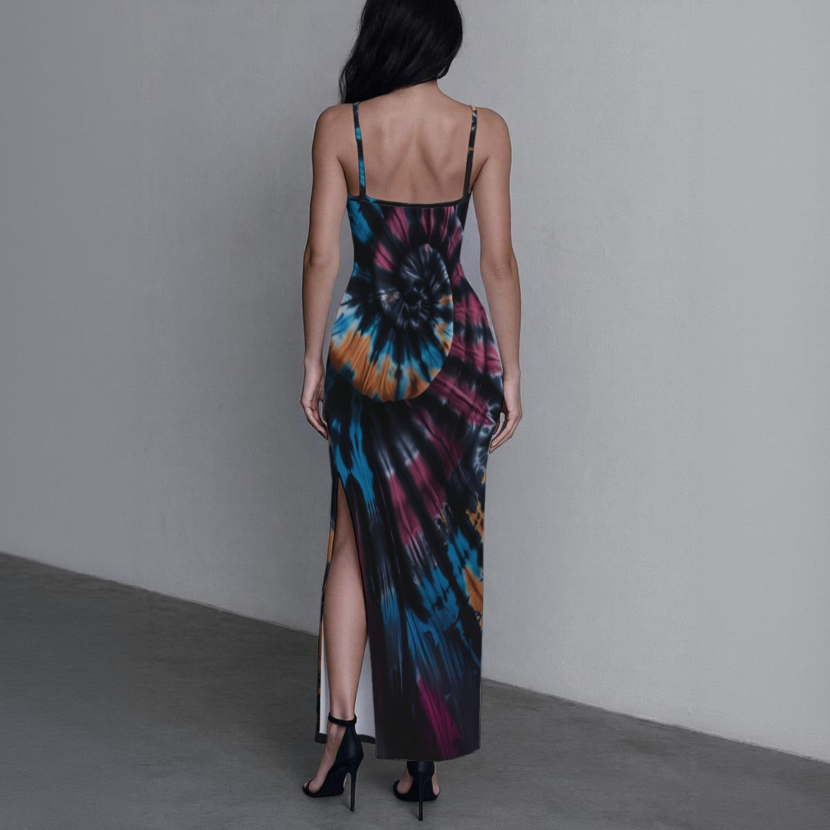 Woman wearing a tie-dye dress with a high slit on a plain background
