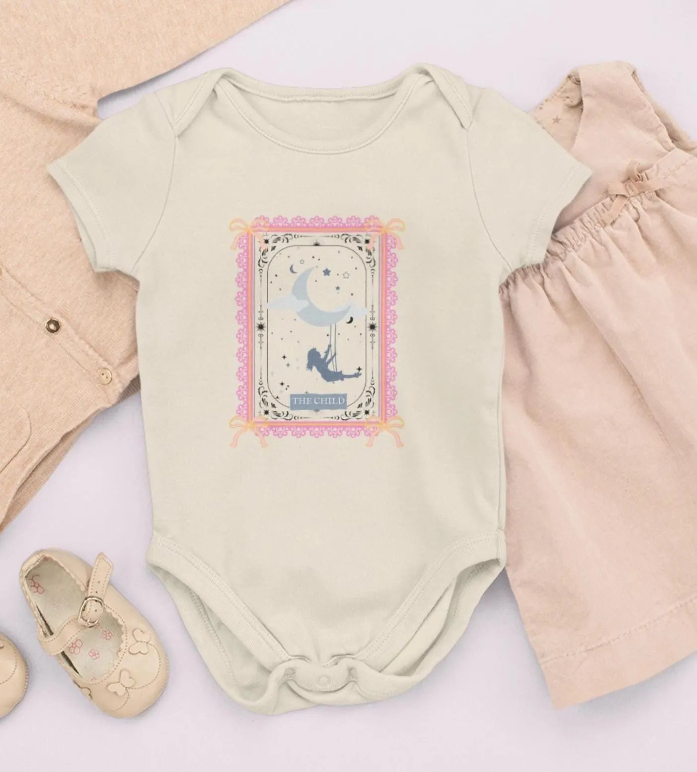 Baby outfit with a onesie, pants, and shoes on a light background