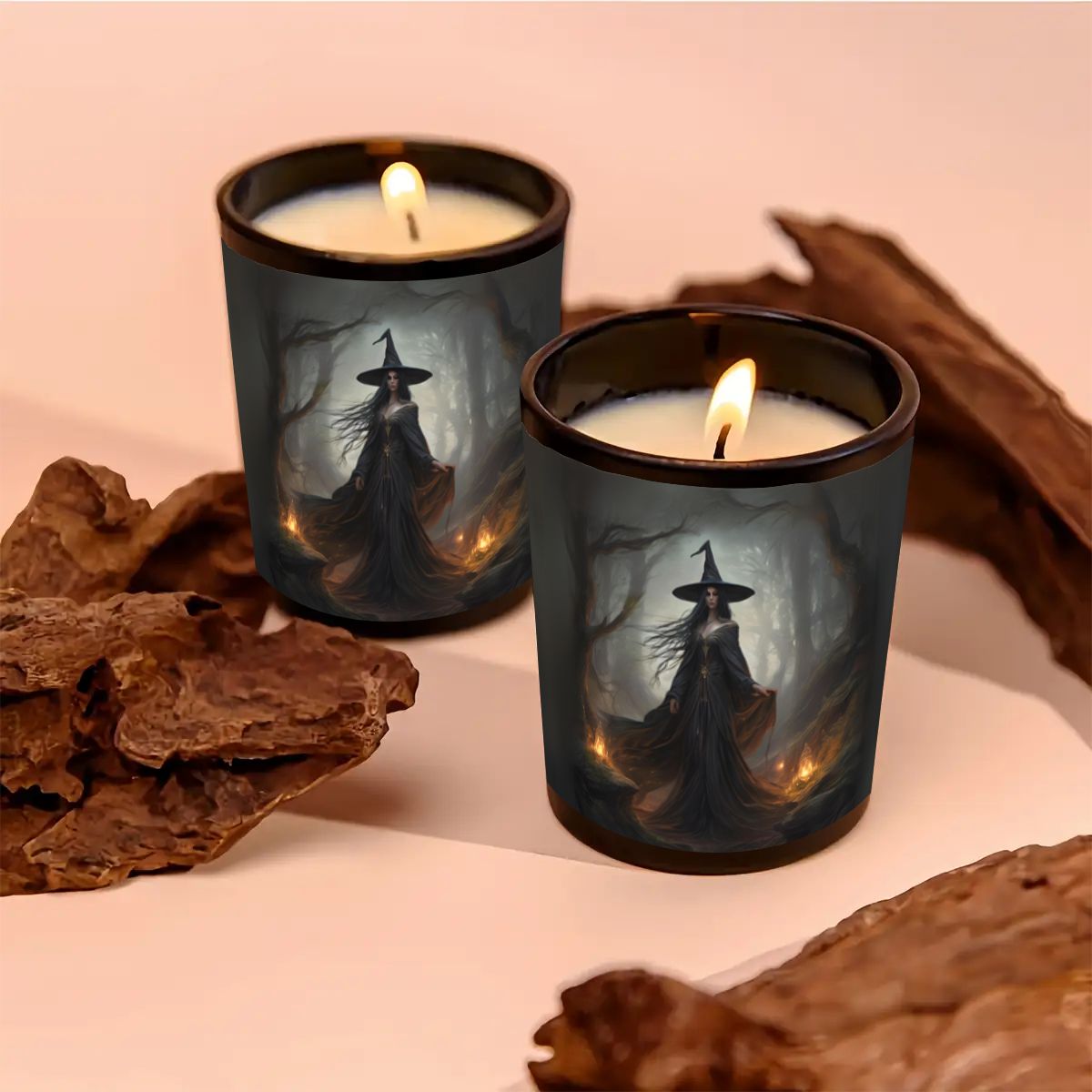 Two lit candles in black holders with witch designs on a pink background