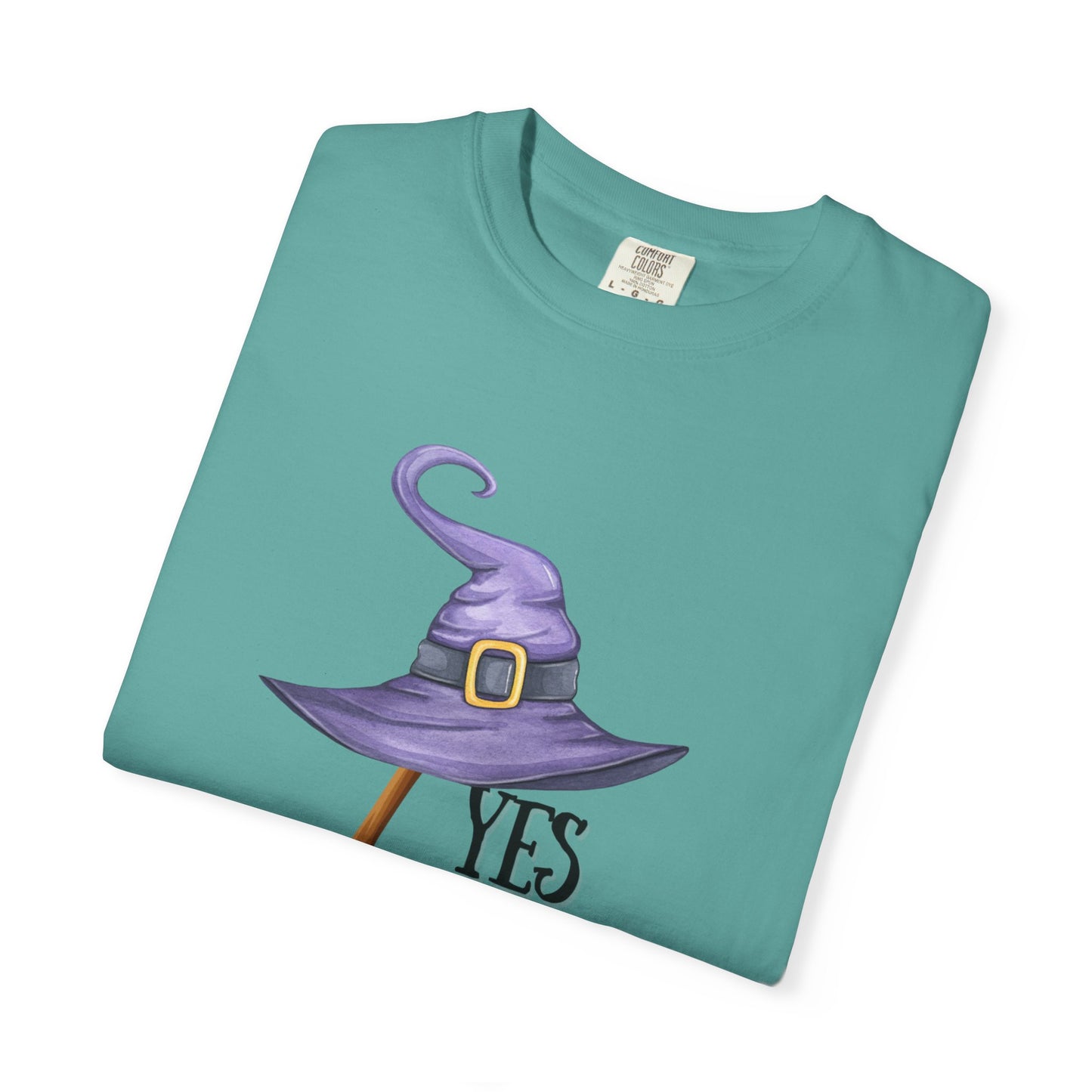 Folded teal t-shirt with a purple witch hat graphic on a white background