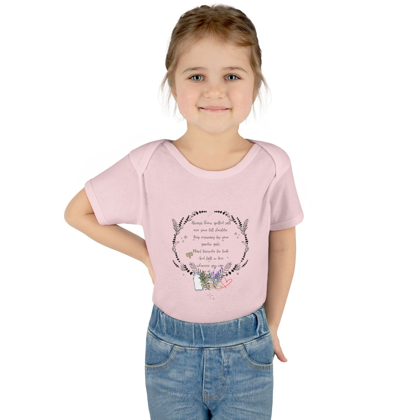 Young girl wearing a pink t-shirt with a design and text, standing against a white background