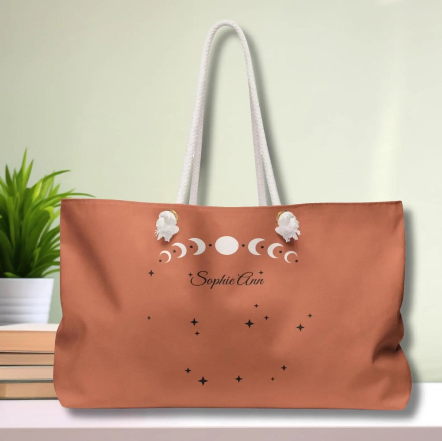 Brown tote bag with star and moon design and 'Sophie Anne' text on a light green background.