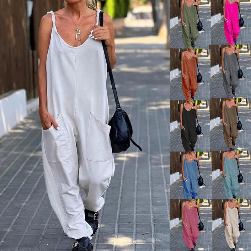 Woman in a white sleeveless jumpsuit walking on a sidewalk with a black bag.