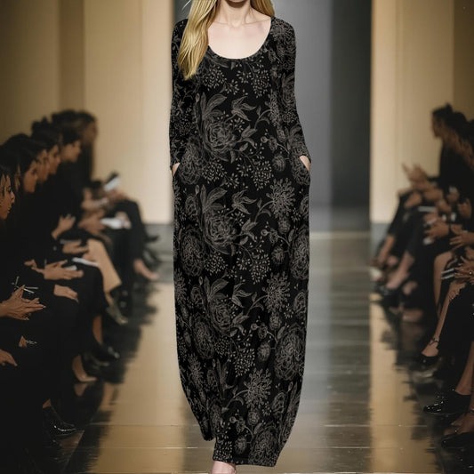 Model wearing a black floral dress on a runway with an audience.