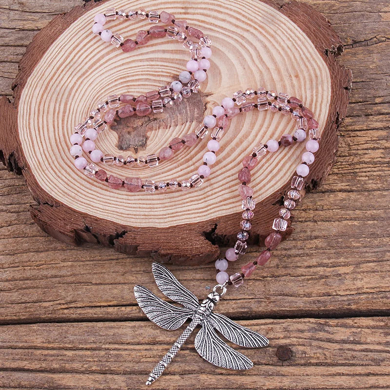 Necklace with pink beads and dragonfly pendant on a wooden surface