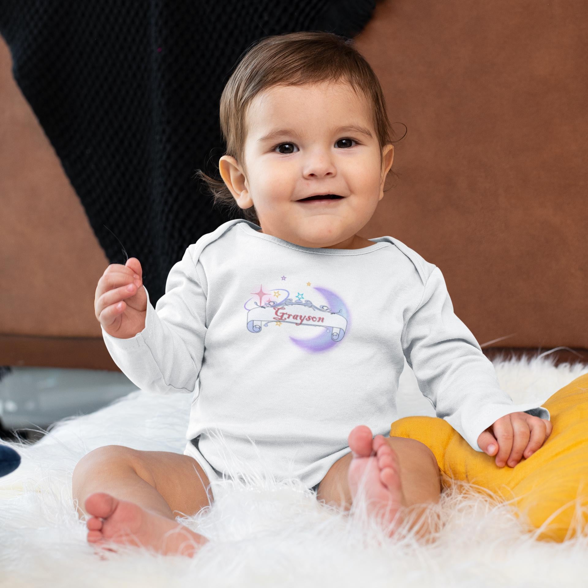 Baby wearing a white onesie with colorful designs and text, sitting on a fluffy surface.
