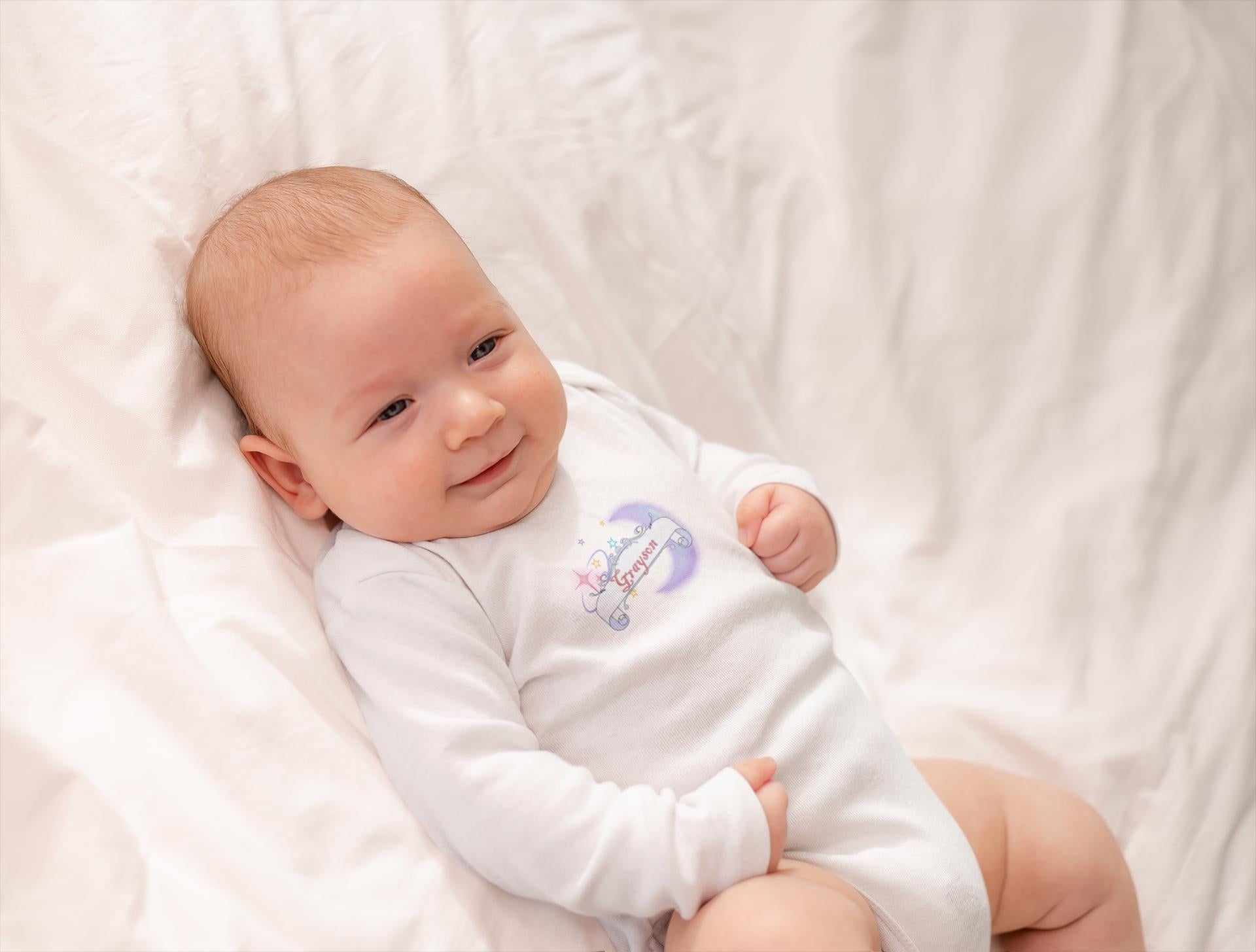 Baby wearing a white onesie with a colorful design on a white blanket