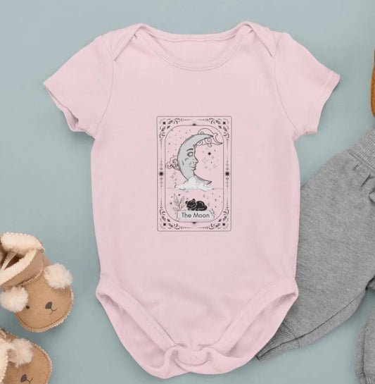 Pink baby onesie with a tarot card design on a light blue background