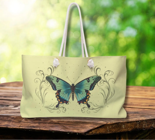 Light green tote bag with butterfly design on a wooden surface with a blurred green background