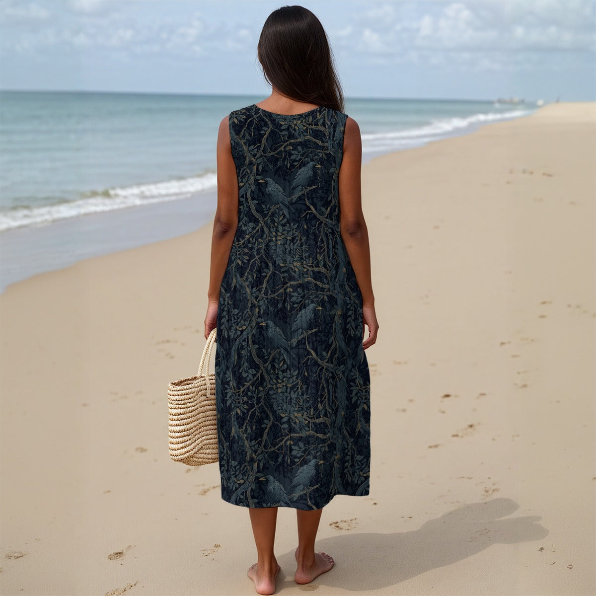 Woman in a dark patterned dress standing on a sandy beach with ocean view