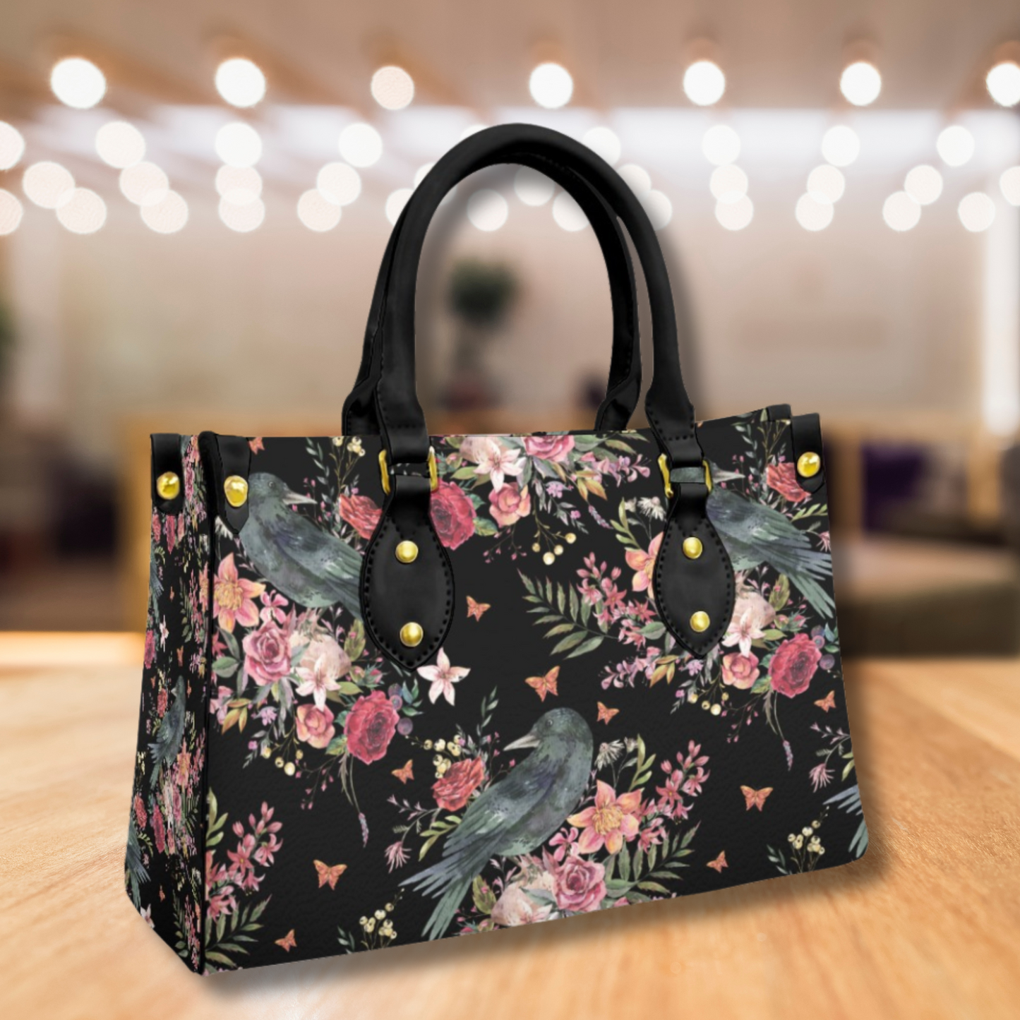 Floral and bird patterned handbag on a wooden surface with blurred lights in the background