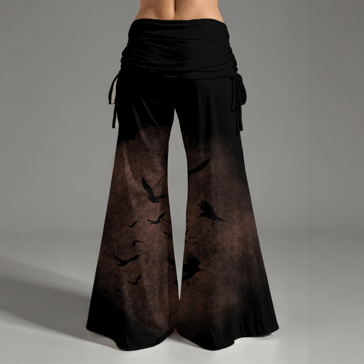Black and brown gradient pants with bird silhouette design on a gray background