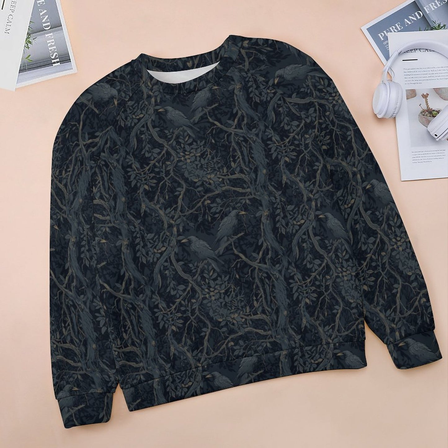 Black patterned sweater on a beige surface with magazines and headphones in the background