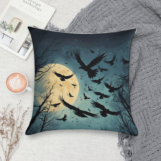 Decorative pillow with a design of crows flying around a moonlit sky, placed on a textured surface.