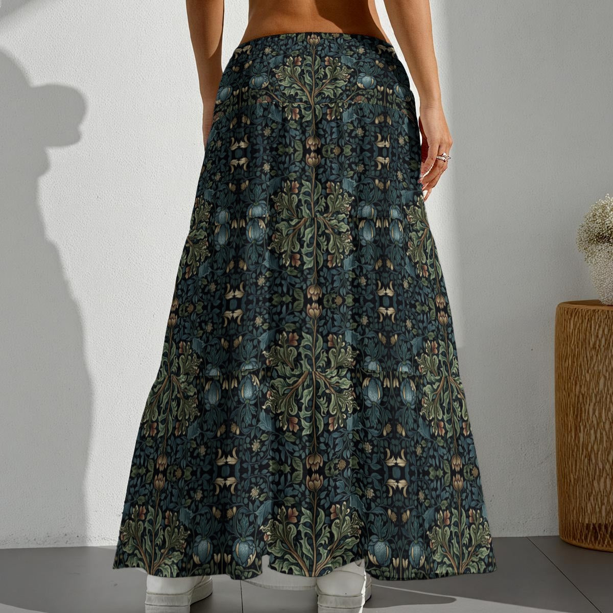 Person wearing a long, patterned skirt with a neutral background