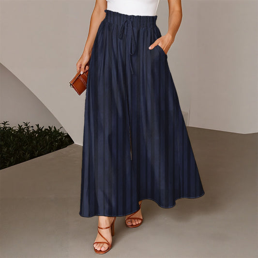 Person wearing a navy blue skirt with a white top and brown sandals on a neutral background