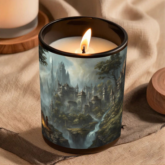 Candle in a jar with a painted design of a castle and landscape, placed on a textured surface.