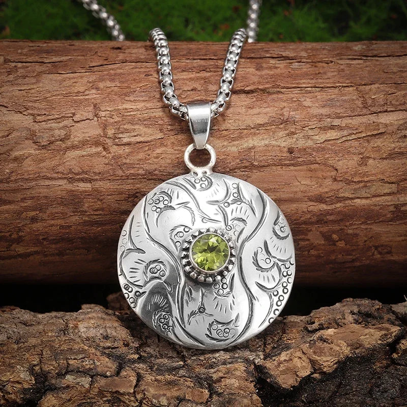 Silver pendant with a green gemstone on a wooden background