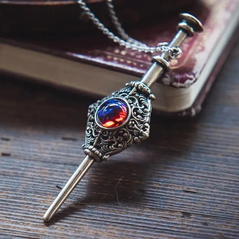 Decorative keychain with a red and blue gem on a wooden surface