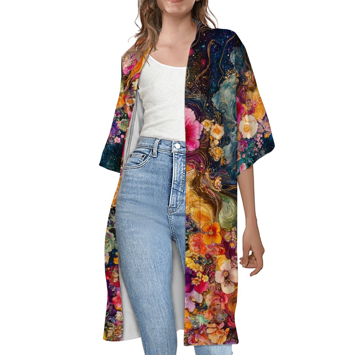 A woman wearing a multicolored floral short sleeve cape with a white top and blue jeans.