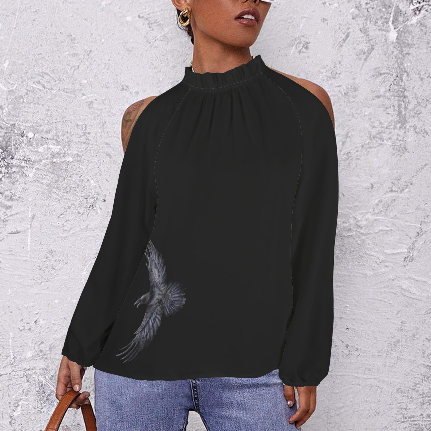 Person wearing a black long-sleeve top with a bird design against a textured gray background