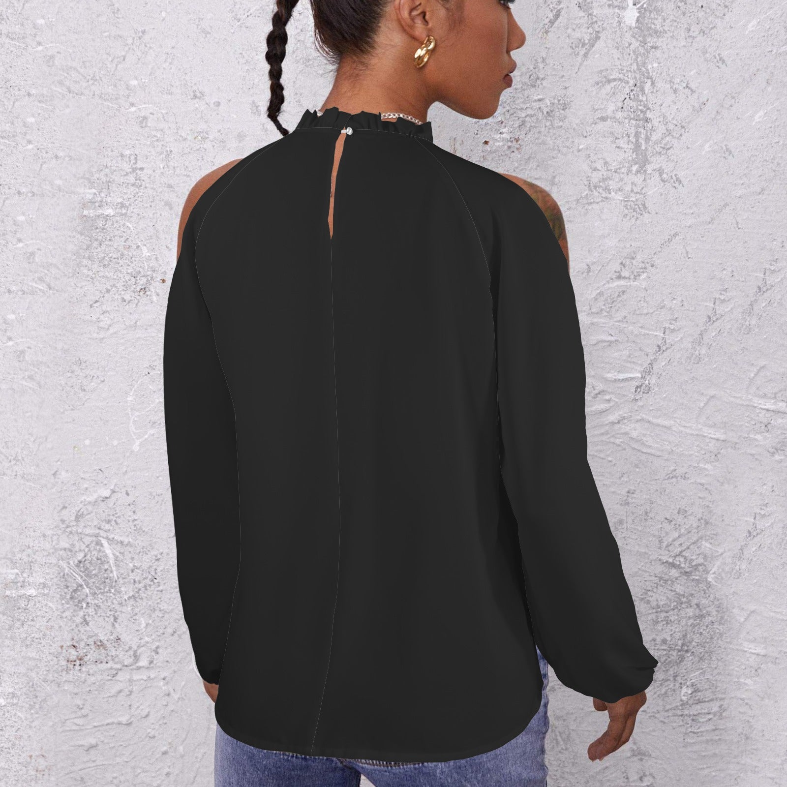 Person wearing a dark patterned long-sleeve top against a textured light gray wall.