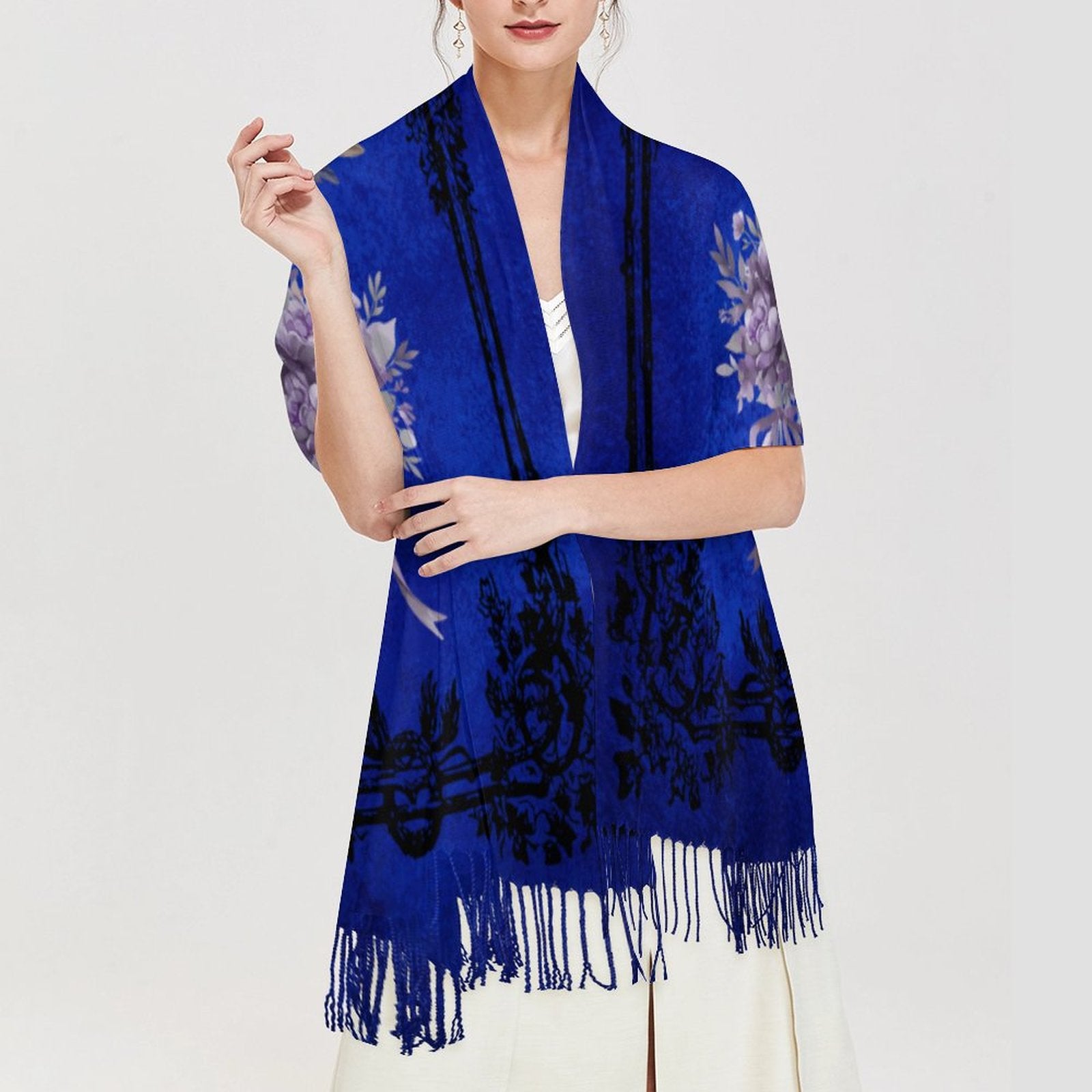 Woman wearing a blue floral-patterned scarf with fringe on a white background