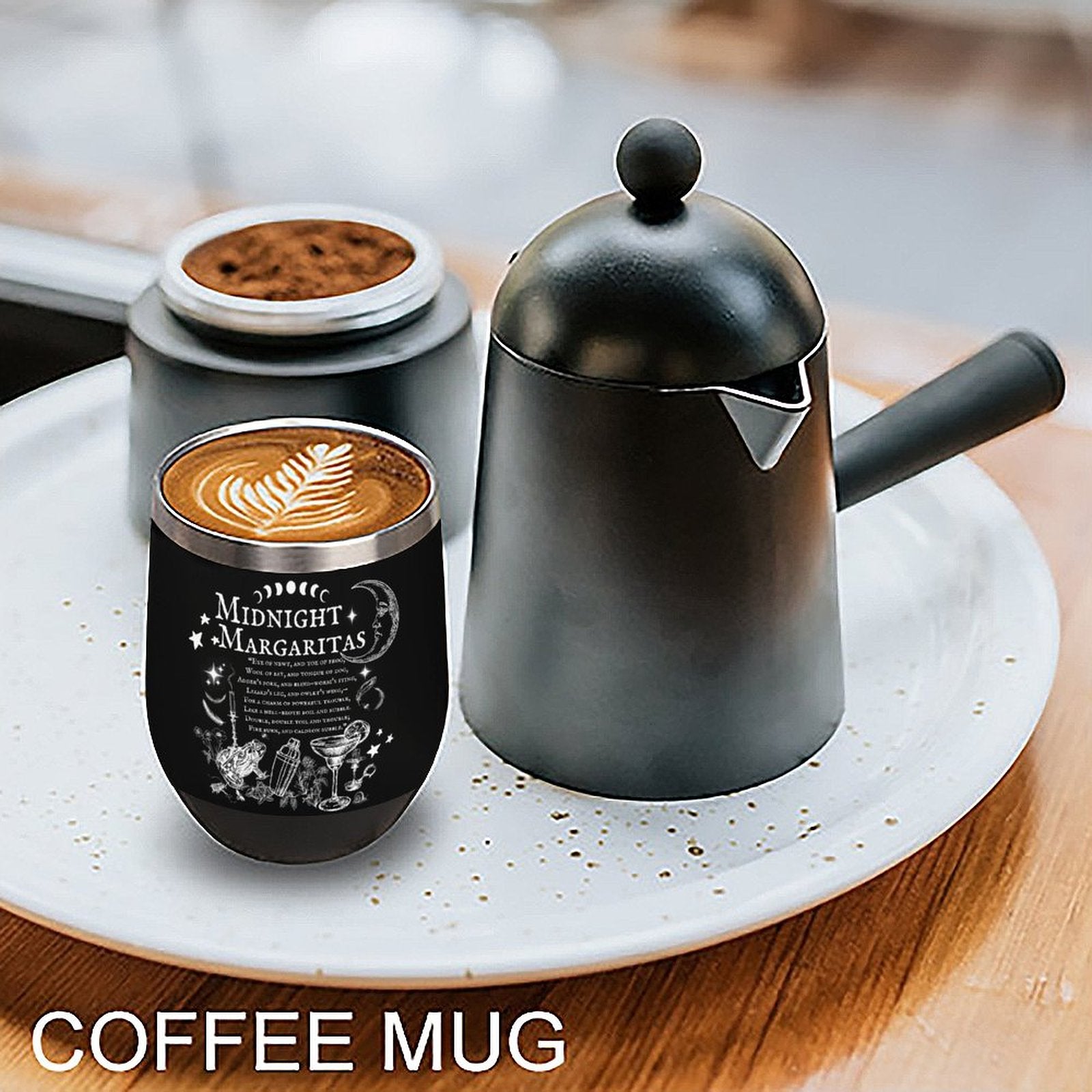 Black coffee mug with a design and a black teapot on a white plate.