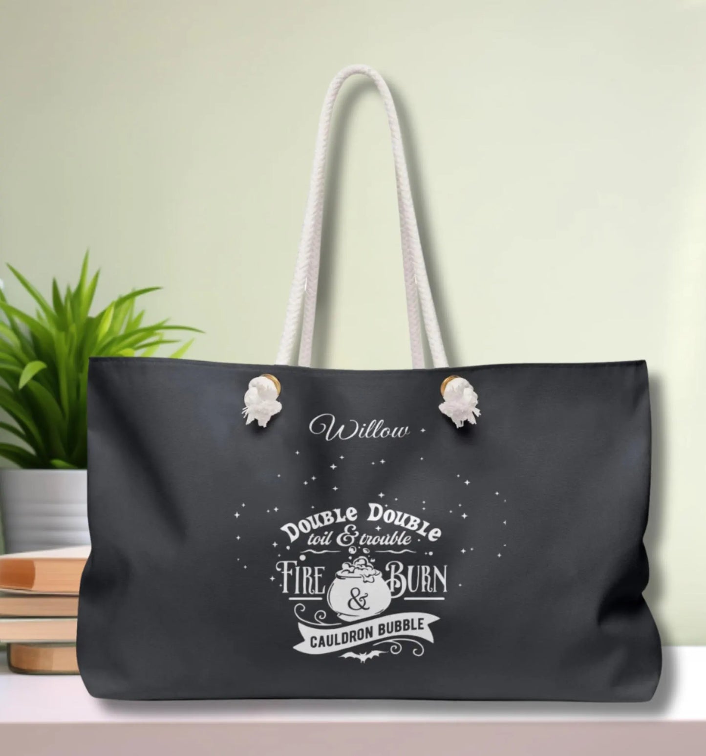 Black tote bag with white text and design on a light green background