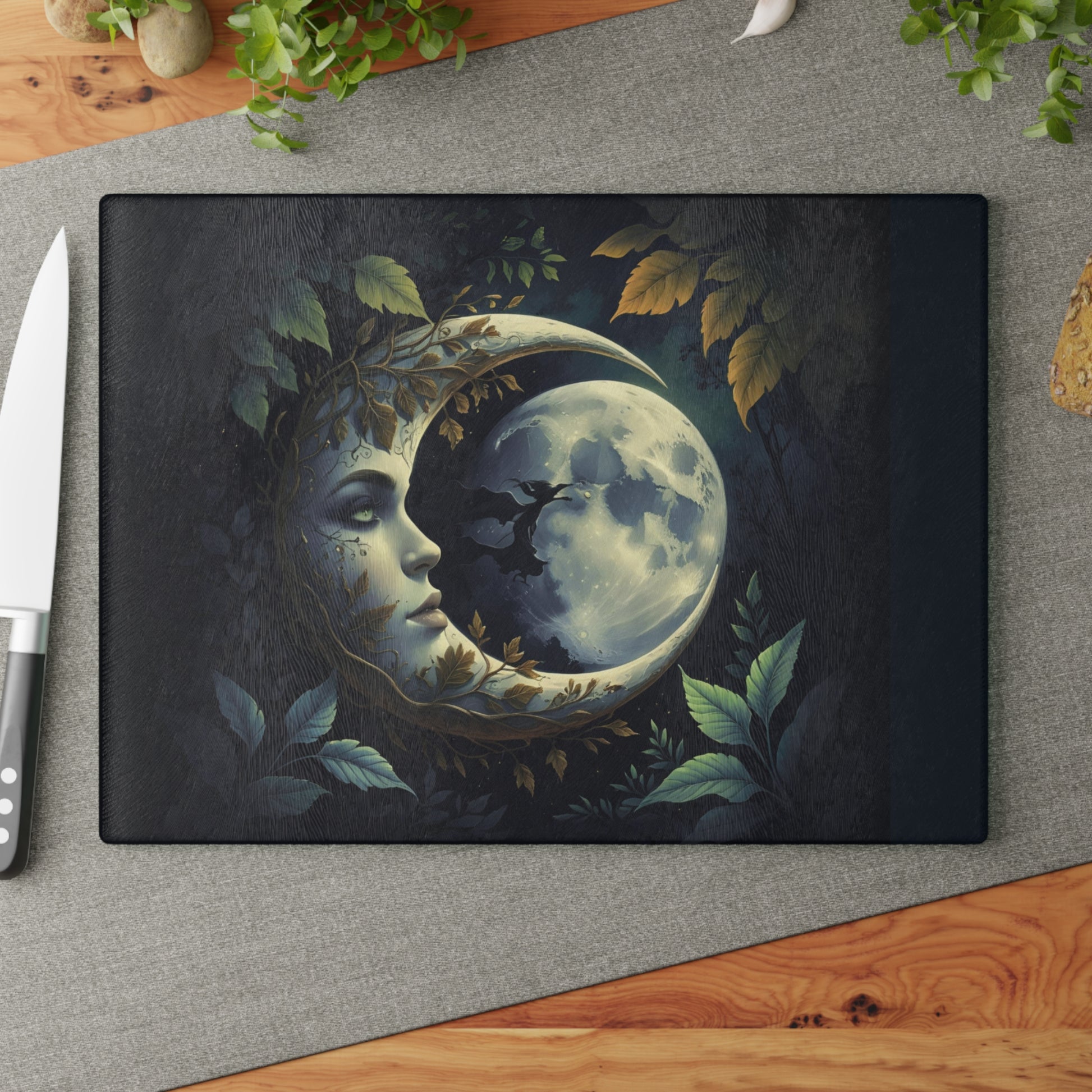 Decorative cutting board with a moon and face design on a gray surface with a knife.