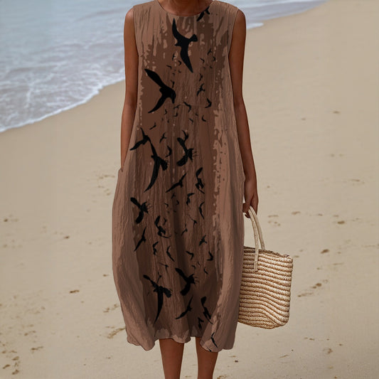 Woman in a beige dress with black bird patterns on a beach