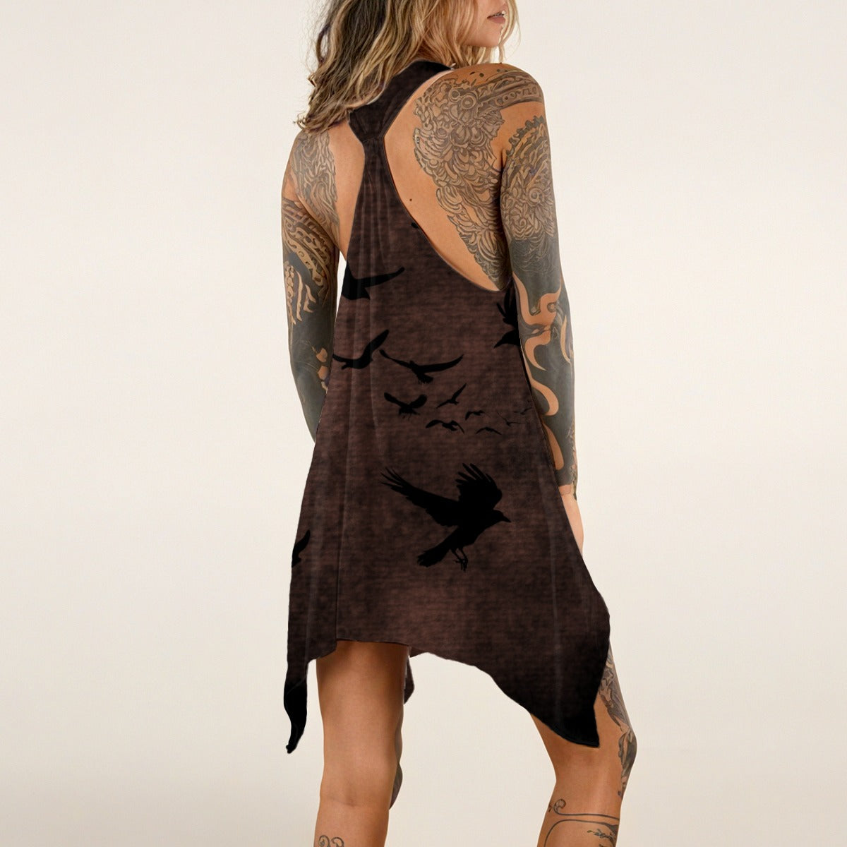 Woman wearing a brown dress with black bird silhouettes and tattoos on a beige background