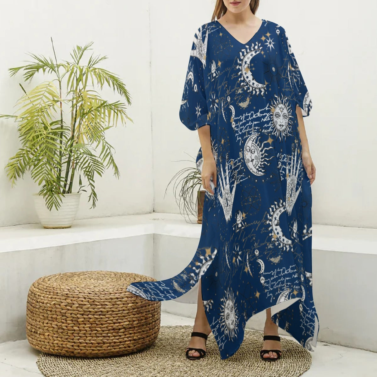 Woman wearing a blue dress with celestial pattern in a room with plants and a woven ottoman.