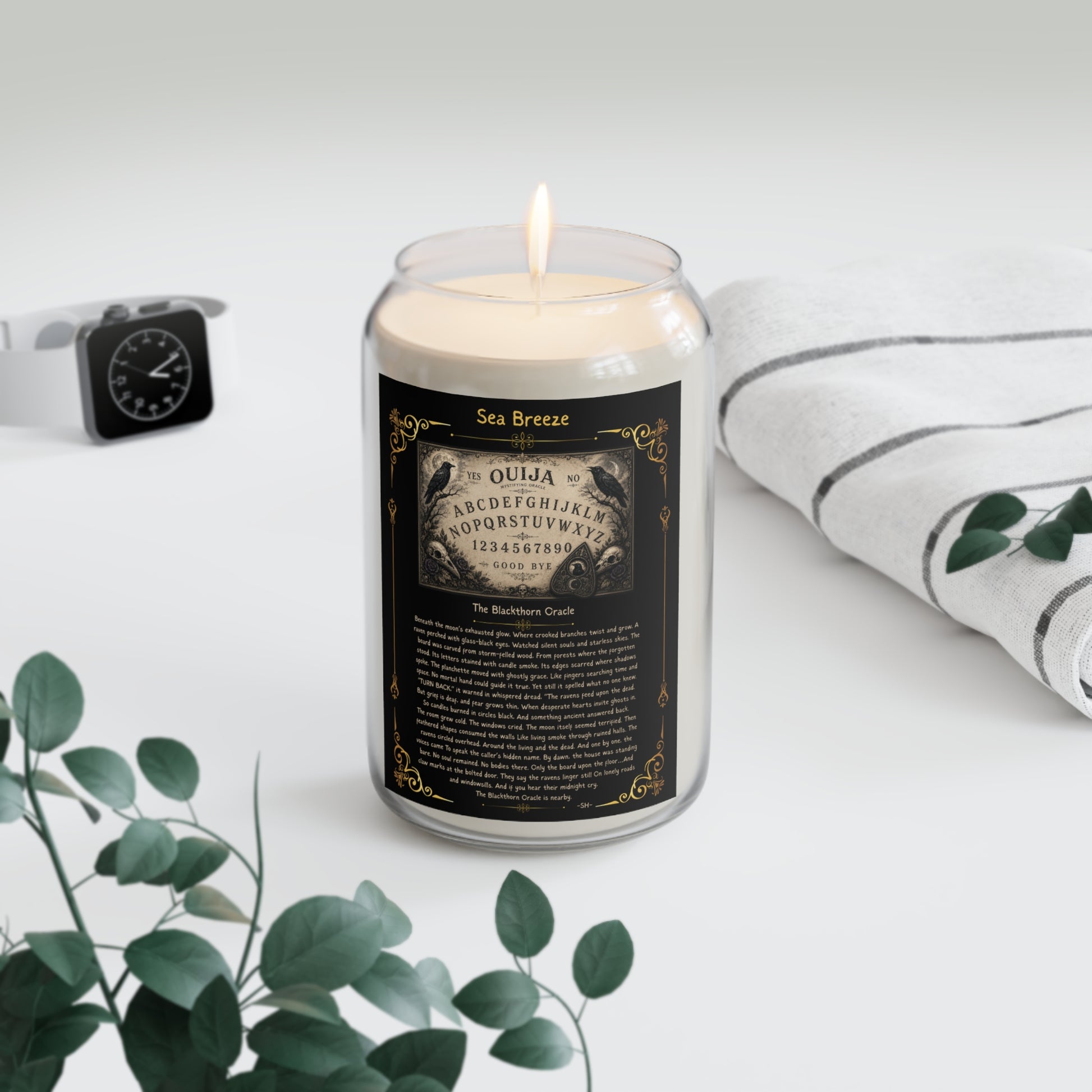 Candle in a glass jar with a decorative label on a white surface with greenery