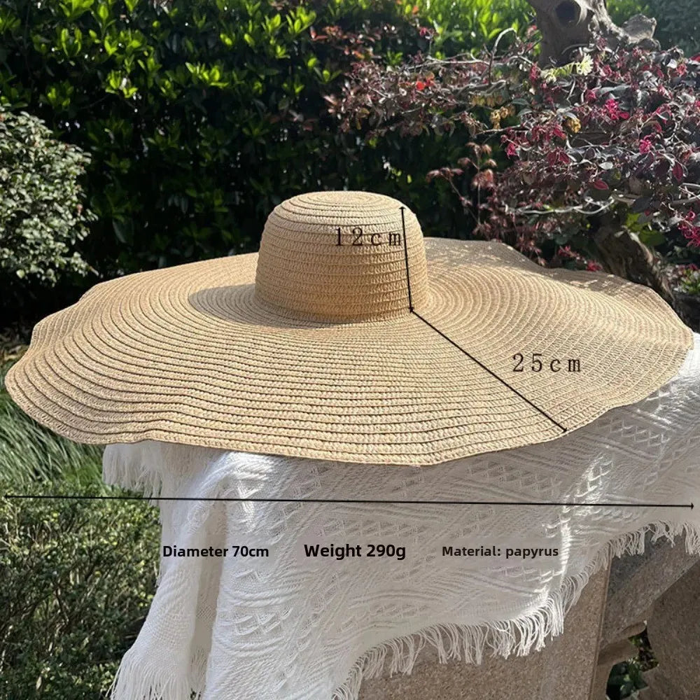 Beige straw hat with measurements and product details on a white surface with greenery in the background