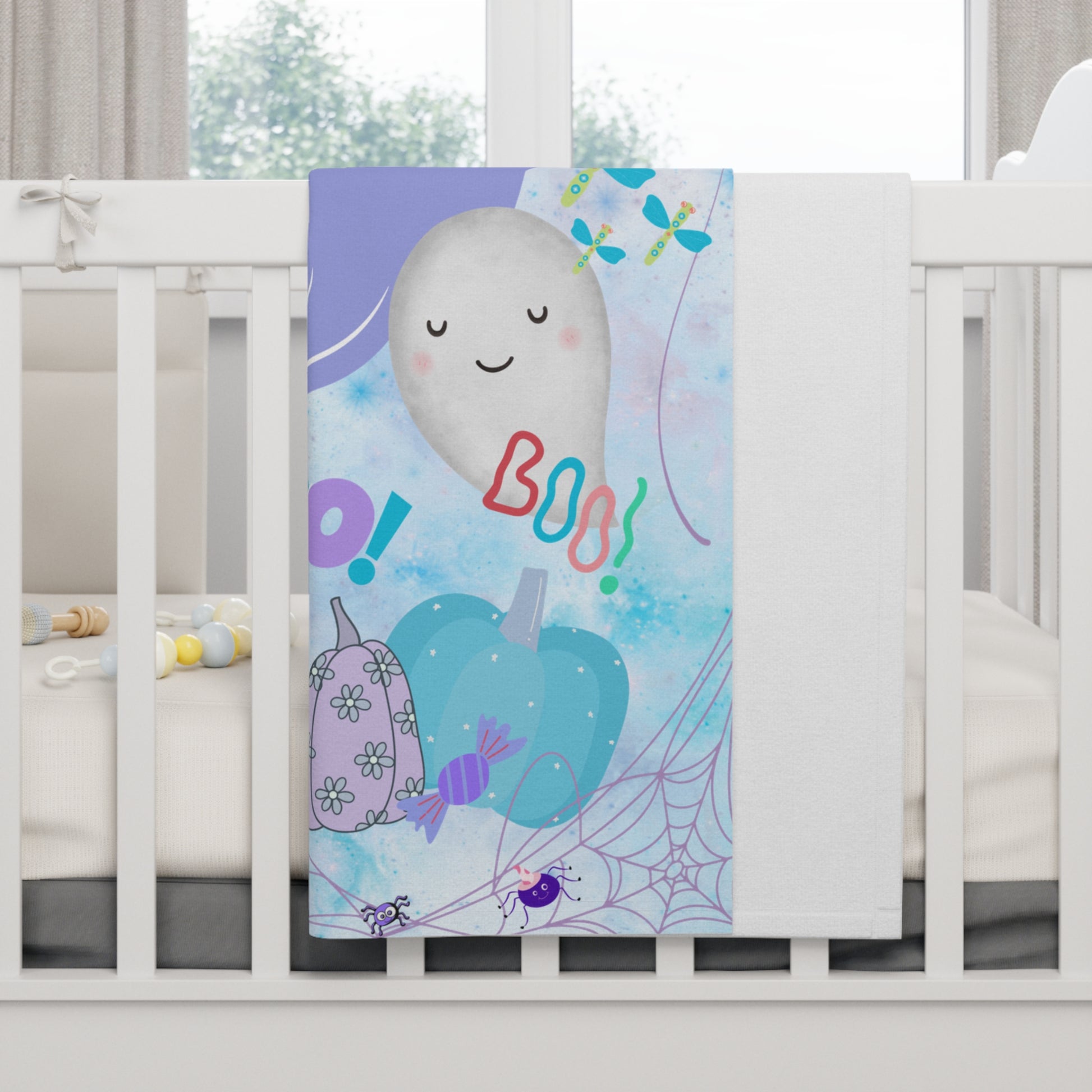 Colorful Halloween-themed blanket with ghost, balloons, and candy on a crib.